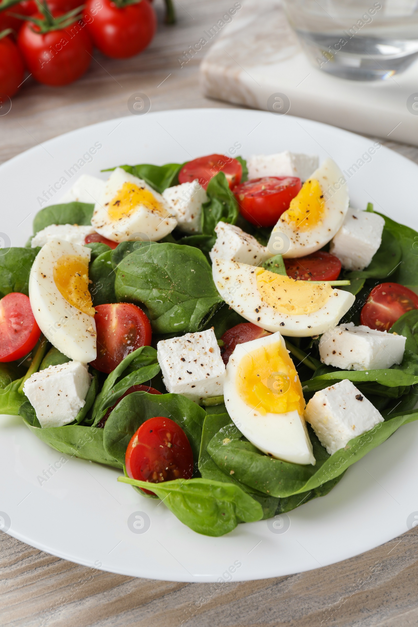 Photo of Delicious salad with boiled eggs, feta cheese and tomatoes on table, closeup