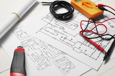 Photo of Wiring diagrams, wires and digital multimeter on white table, closeup