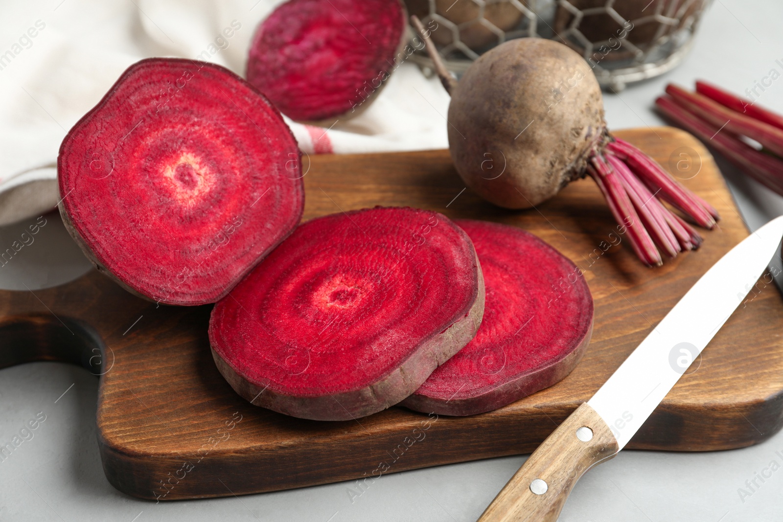 Photo of Cut raw beet and knife on light grey table