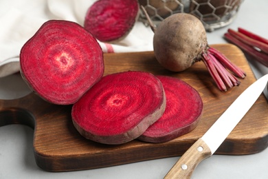 Cut raw beet and knife on light grey table