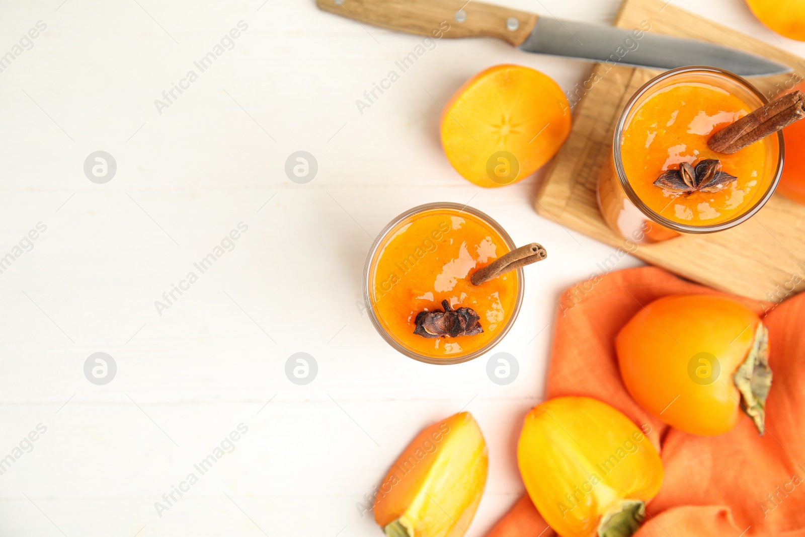 Photo of Tasty persimmon smoothie with anise and cinnamon on white wooden table, flat lay. Space for text