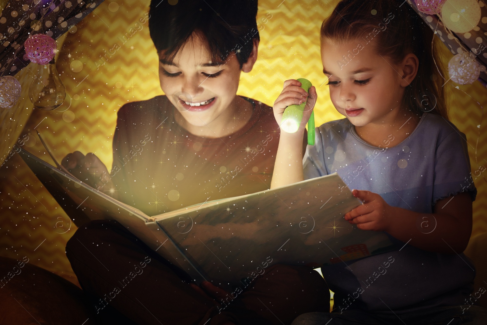 Image of Cute little children reading magic book in play tent