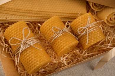 Photo of Beautiful yellow beeswax candles and sheets in box, above view
