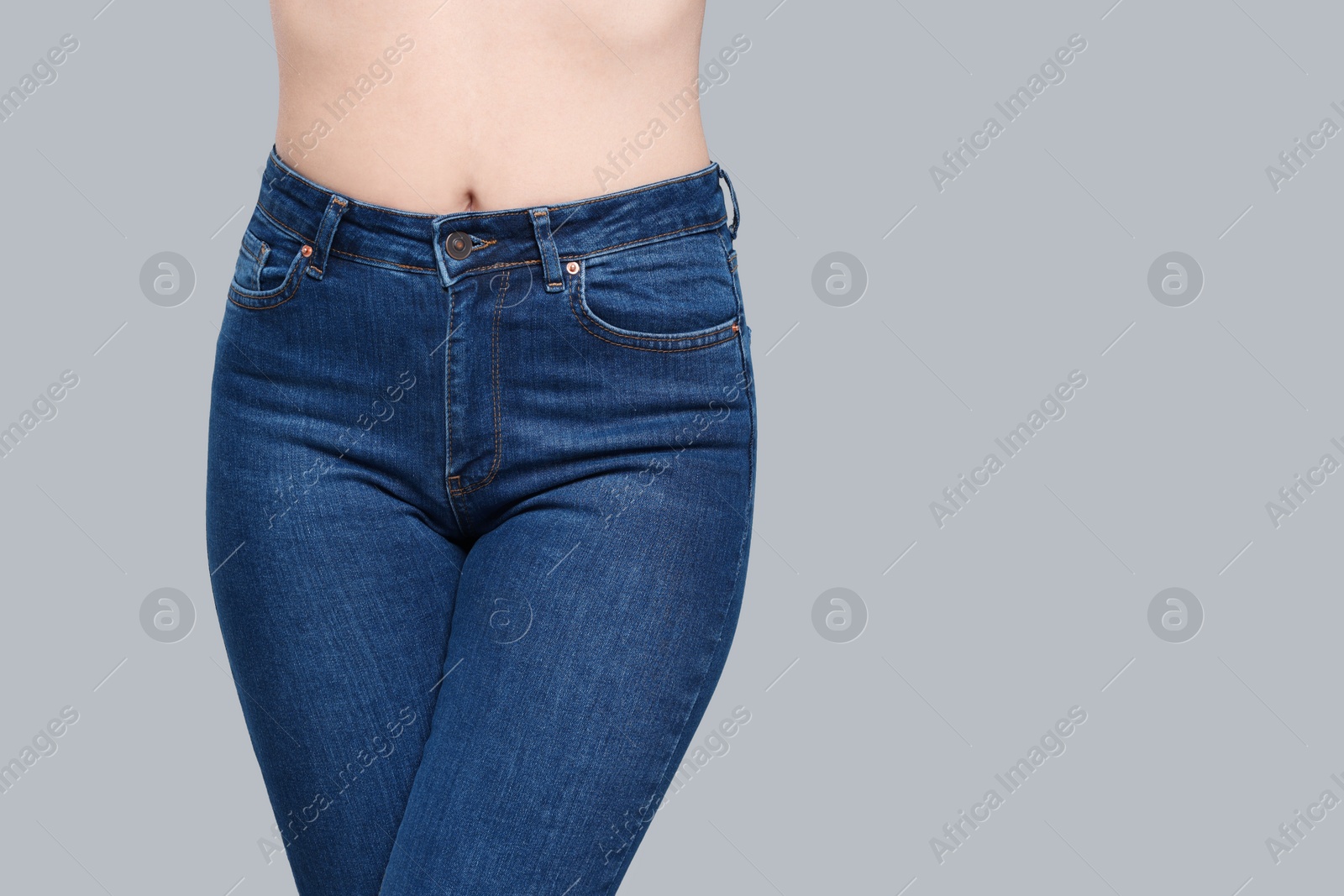 Photo of Woman in stylish jeans on grey background, closeup. Space for text