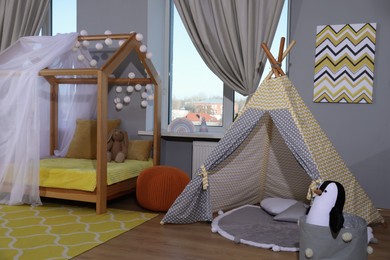 Photo of Stylish child room interior with comfortable house bed and play tent