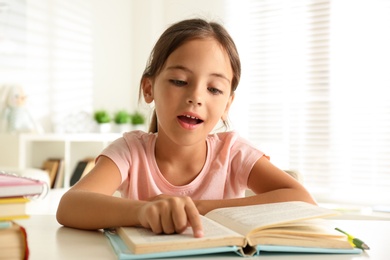 Little girl doing homework at table indoors