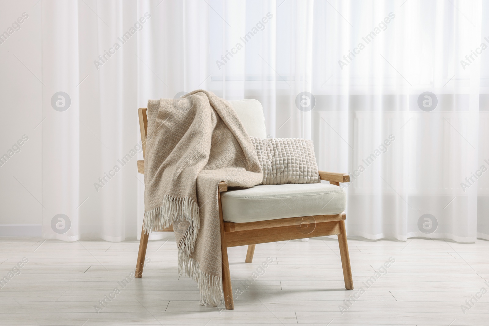 Photo of Comfortable armchair with blanket and pillow in room