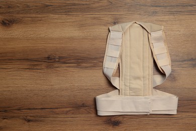 Beige posture corrector on wooden table, top view. Space for text