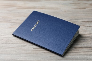 Photo of Blank blue passport on wooden table, closeup