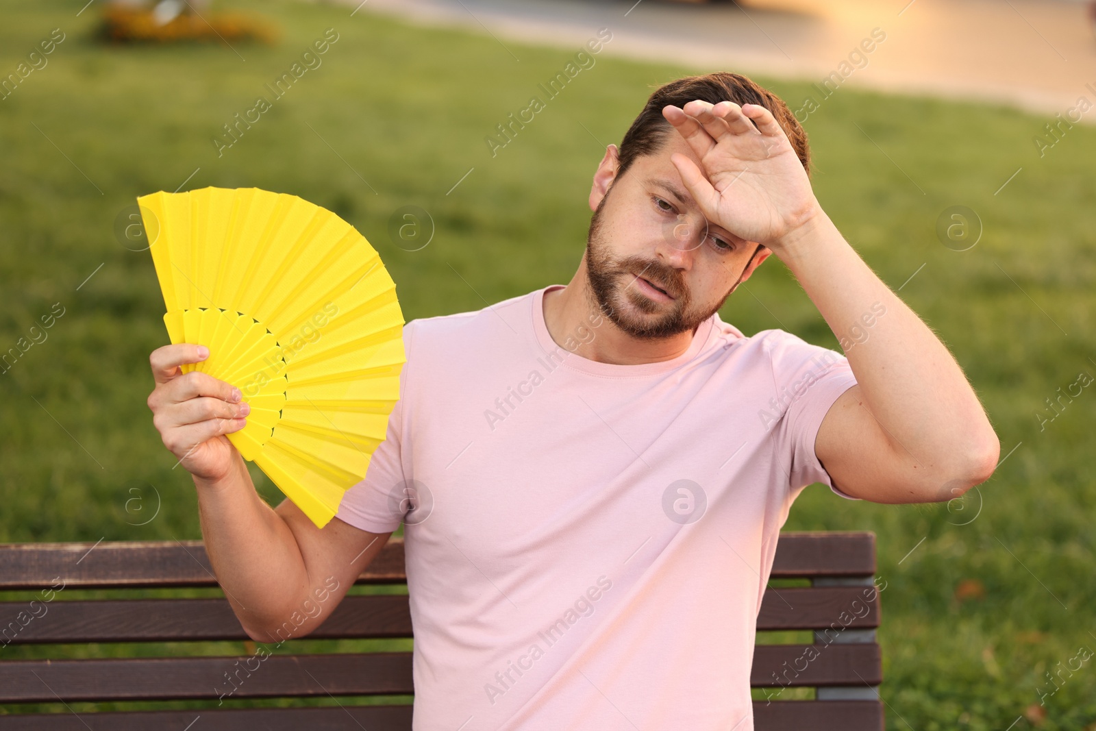 Photo of Man with hand fan suffering from heat outdoors