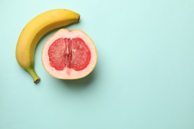 Photo of Banana and half of grapefruit on turquoise background, flat lay with space for text. Sex concept
