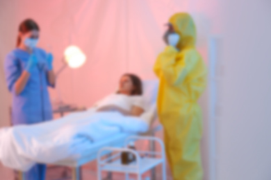 Blurred view of professional paramedics examining patient with virus in quarantine ward