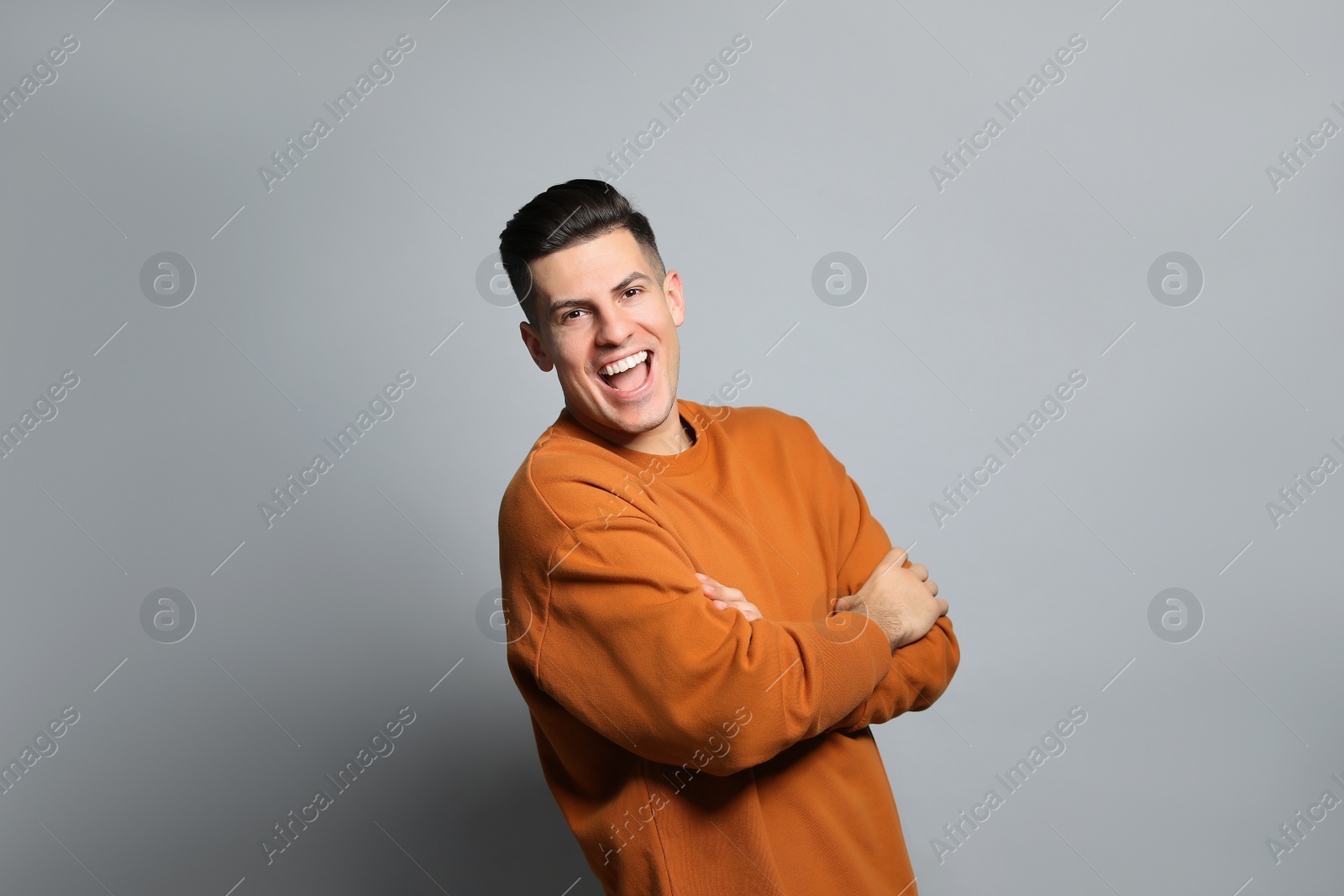 Photo of Handsome man laughing on grey background. Funny joke