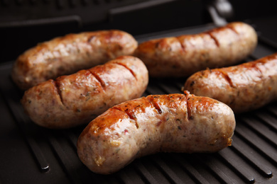 Photo of Cooking delicious sausages on modern grill, closeup