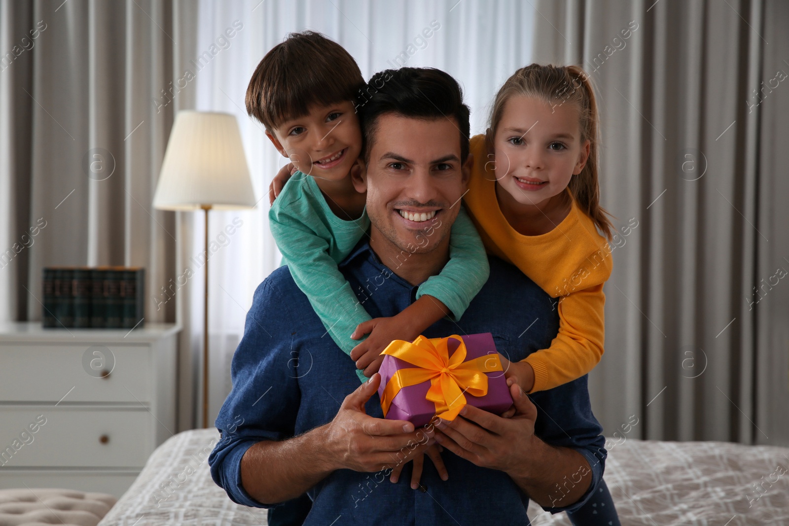 Photo of Man receiving gift for Father's Day from his children at home