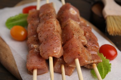 Photo of Skewers with cut raw marinated meat on wooden table, closeup
