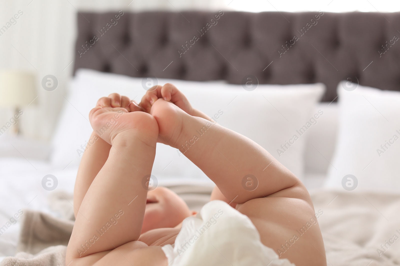 Photo of Cute little baby lying on bed, closeup of legs