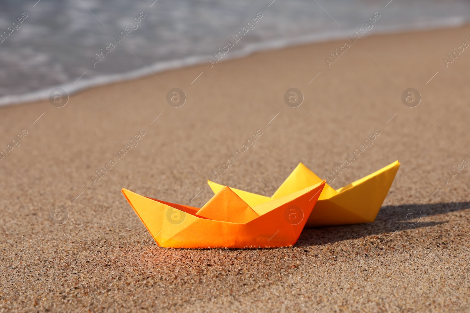 Photo of Bright color paper boats on sandy beach near sea