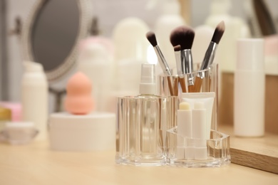 Photo of Organizer with cosmetic products and makeup accessories on dressing table indoors