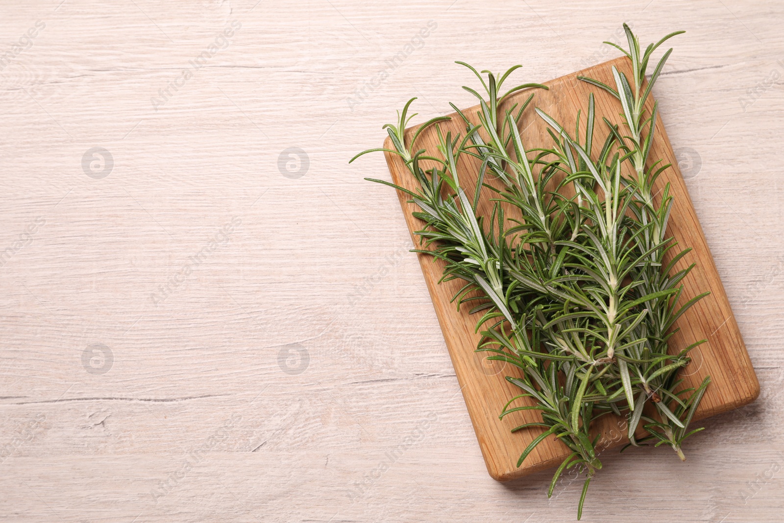 Photo of Sprigs of fresh rosemary on white wooden table, top view. Space for text