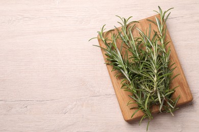 Sprigs of fresh rosemary on white wooden table, top view. Space for text