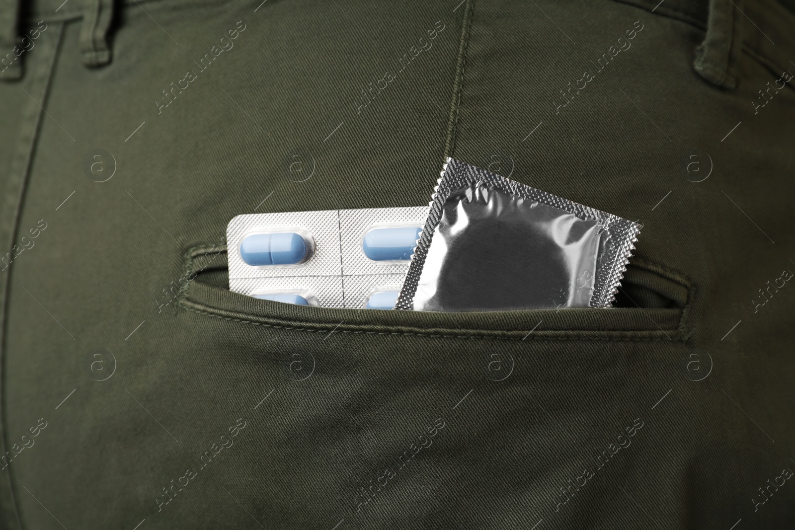 Photo of Jeans with pills and condom in pocket, closeup. Potency problem