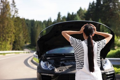 Photo of Woman near broken car outdoors, back view. Space for text