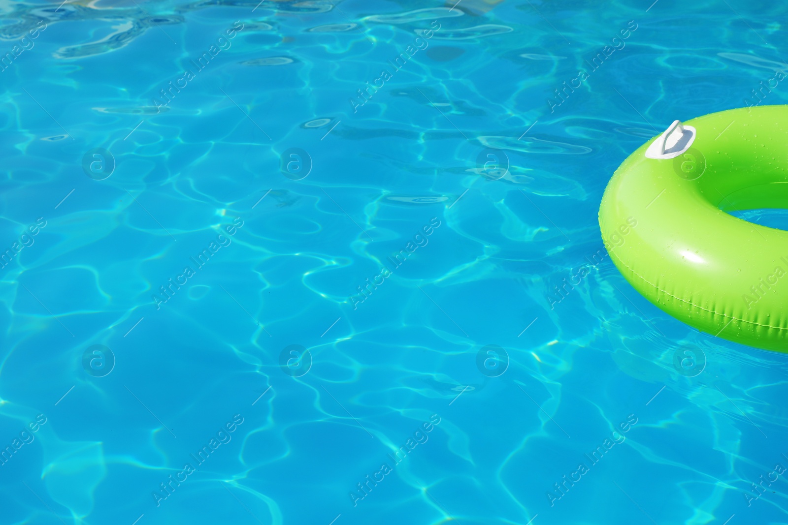 Photo of Inflatable ring floating in swimming pool on sunny day. Space for text