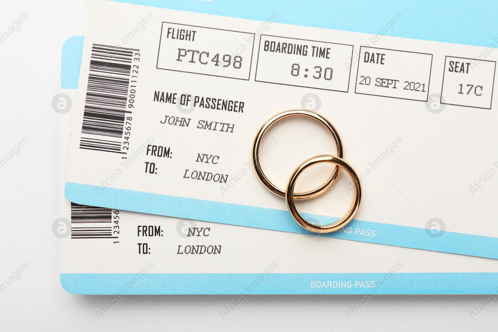 Photo of Honeymoon concept. Plane tickets and two golden rings on white background, top view