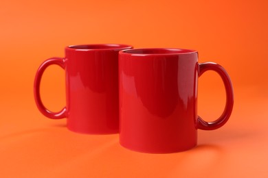 Two red ceramic mugs on orange background