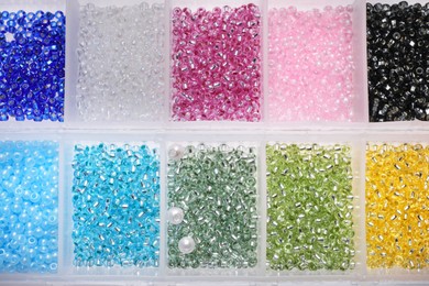 Photo of Plastic organizers with different beads as background, top view