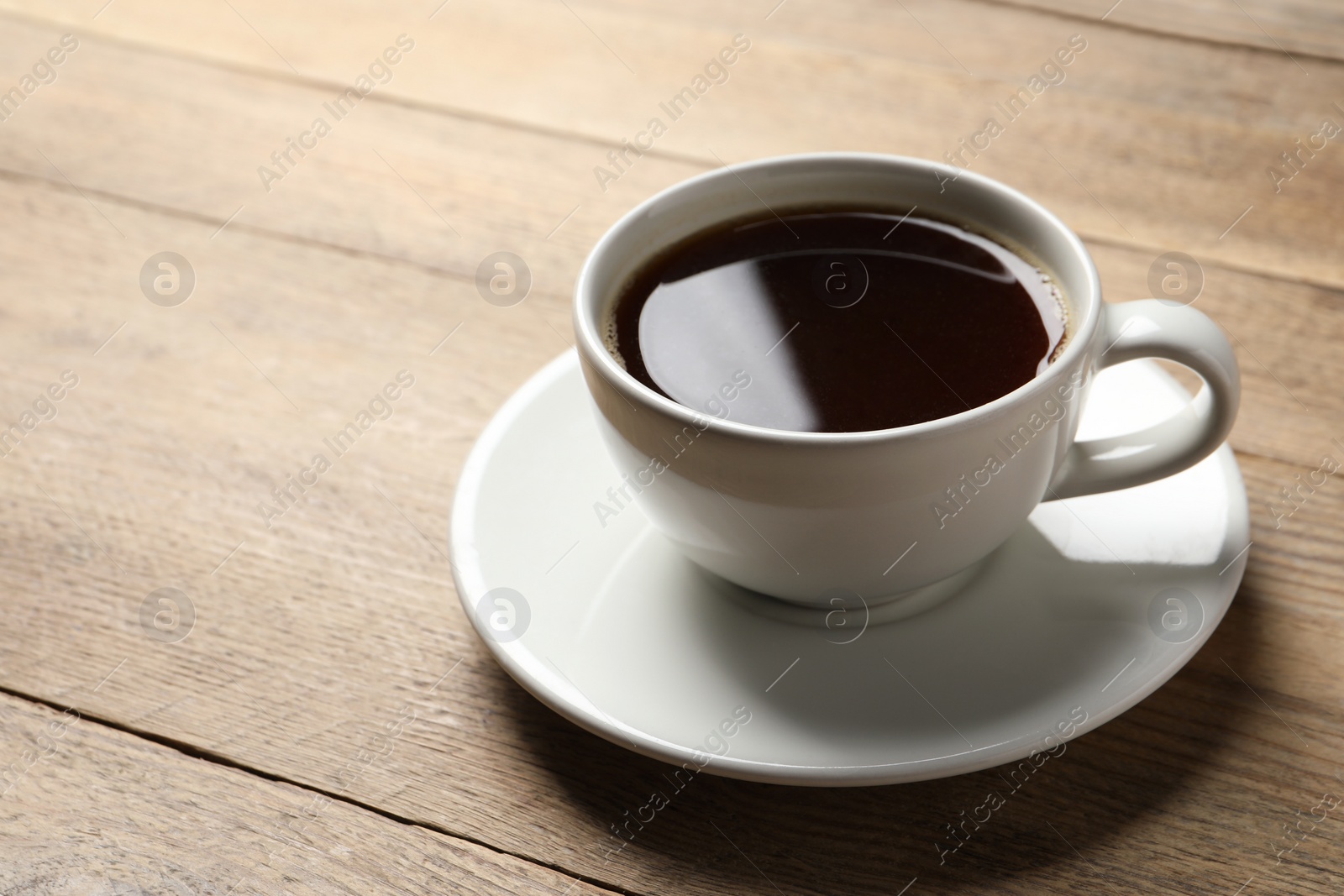 Photo of Cup of aromatic coffee on wooden table. Space for text