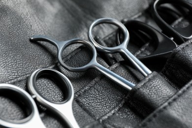 Photo of Hairdresser tools. Professional scissors in leather organizer, closeup