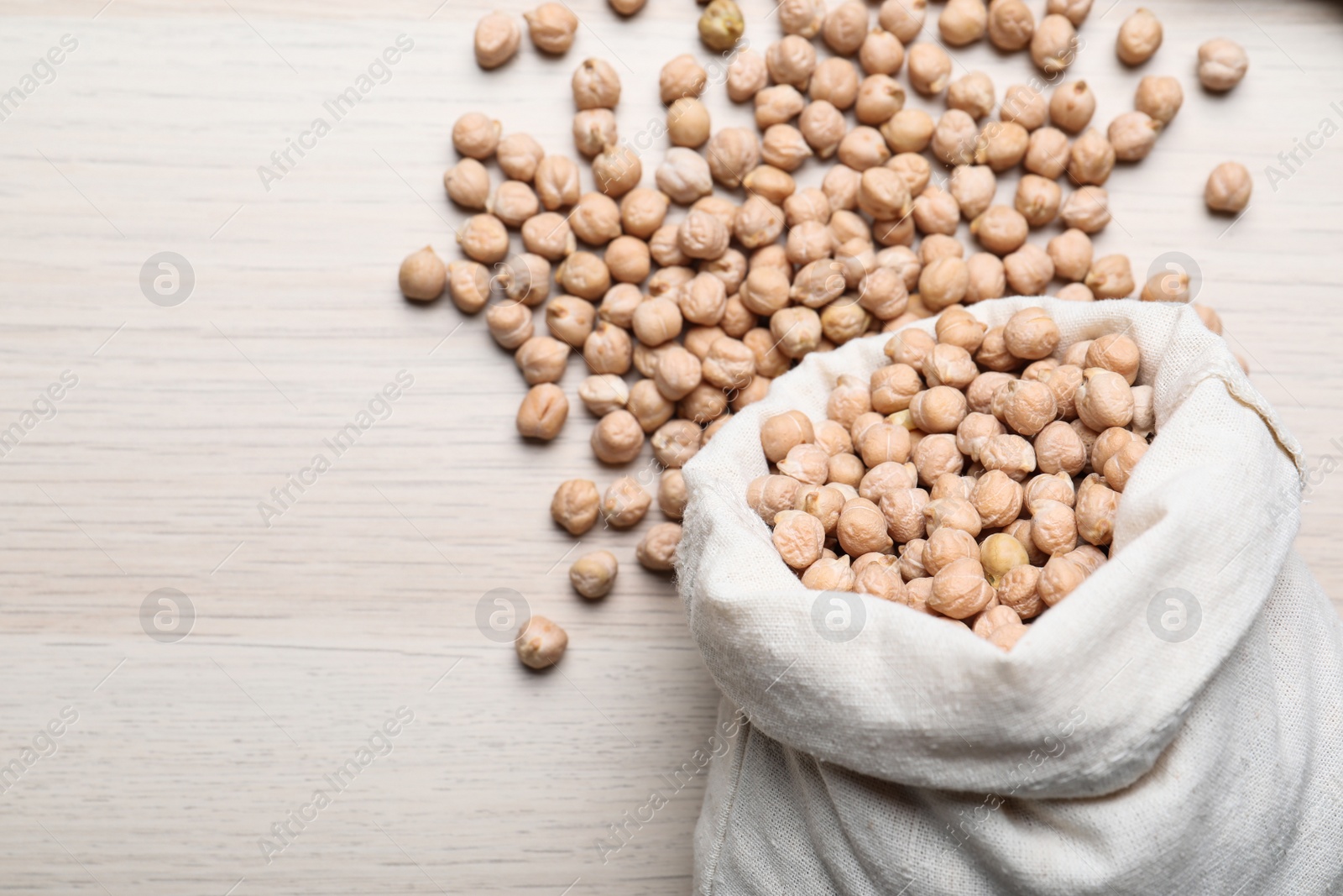 Photo of Sack with chickpeas on wooden table, flat lay. Space for text