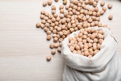 Photo of Sack with chickpeas on wooden table, flat lay. Space for text