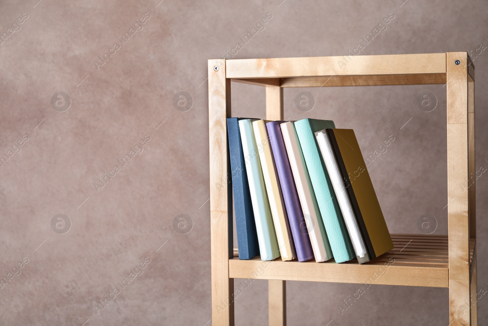 Photo of Different books on shelf against color background. Space for text