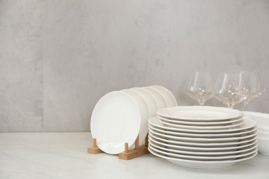Photo of Clean plates and glasses on white marble table, space for text