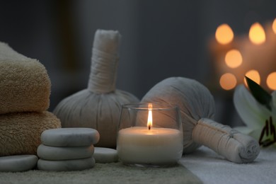 Photo of Spa composition with burning candle and herbal bags on massage table in wellness center