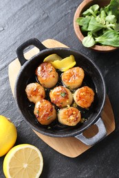 Photo of Delicious fried scallops, lemons and corn salad on dark gray textured table, flat lay