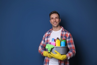 Photo of Man with basin of detergents on color background. Space for text