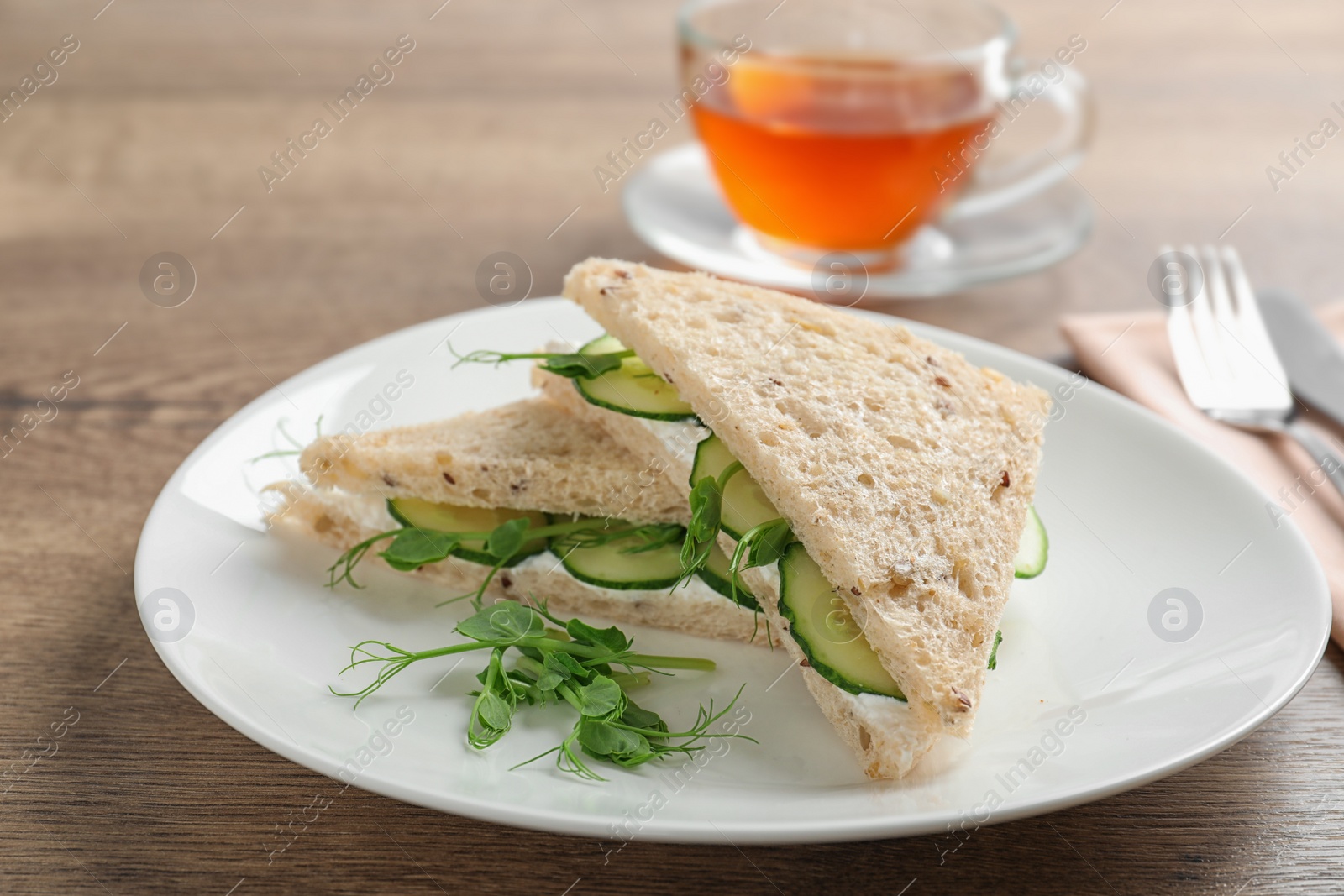 Photo of Plate with tasty cucumber sandwiches served on wooden table