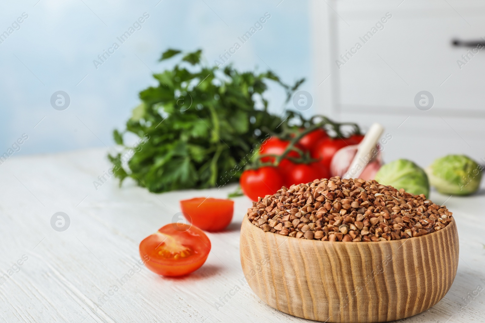 Photo of Buckwheat grains on white wooden table indoors. Space for text