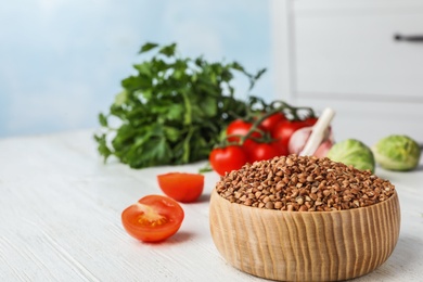 Photo of Buckwheat grains on white wooden table indoors. Space for text