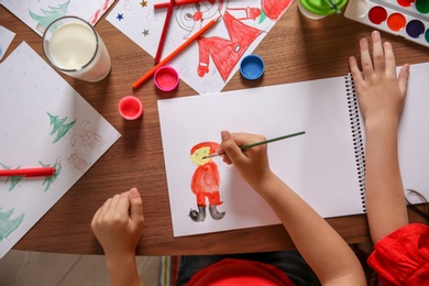 Photo of Little child drawing picture at table, top view. Christmas celebration