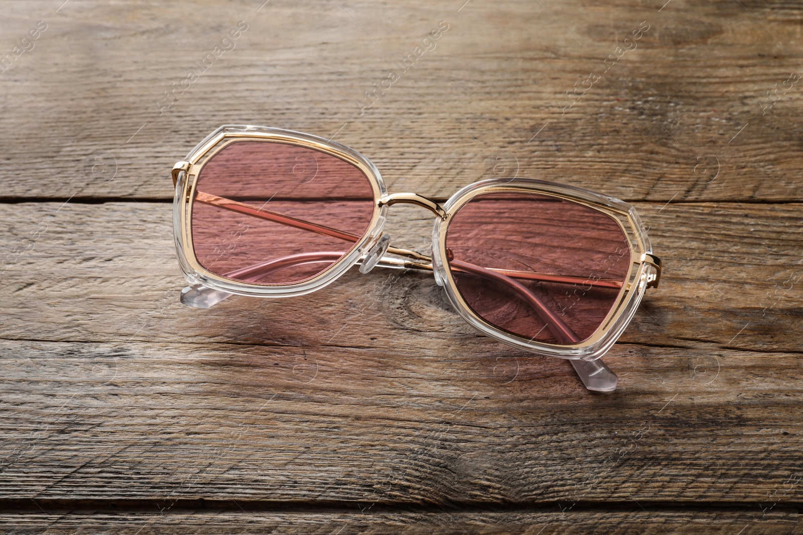 Photo of New stylish sunglasses on wooden table, above view