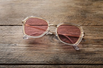 New stylish sunglasses on wooden table, above view