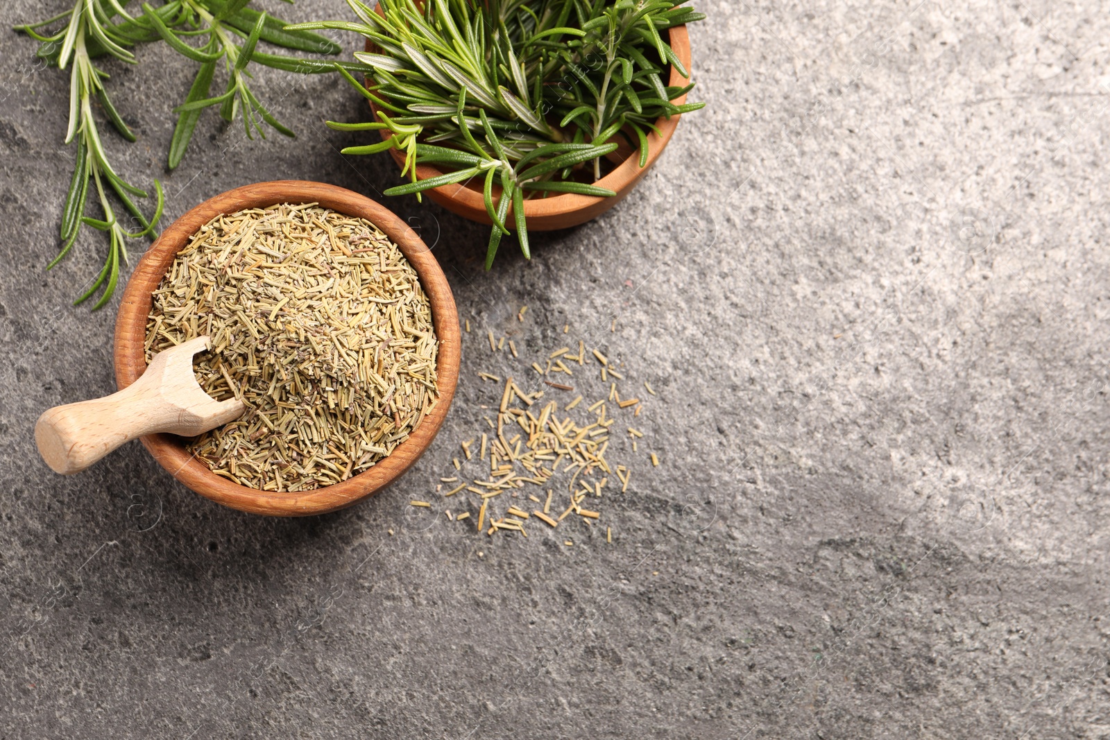 Photo of Bowls with fresh and dry rosemary on grey table, flat lay. Space for text