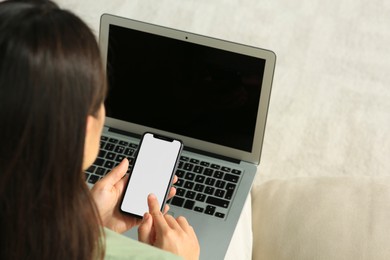 Photo of Young woman with smartphone and laptop indoors, closeup