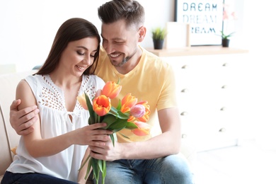 Happy woman receiving flowers from her husband at home