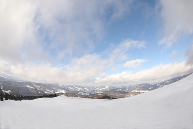 Picturesque mountain landscape with snowy hills under cloudy sky